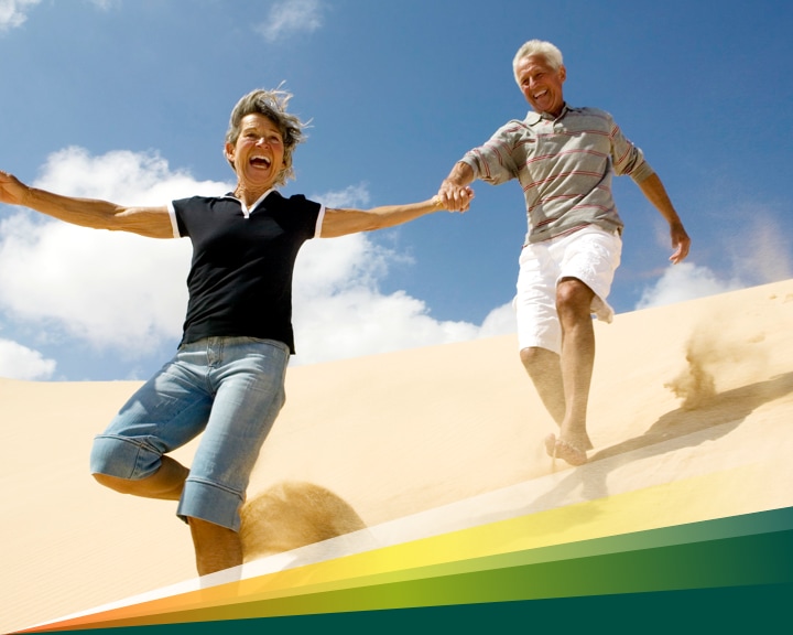 Older couple racing down a desert sand dune